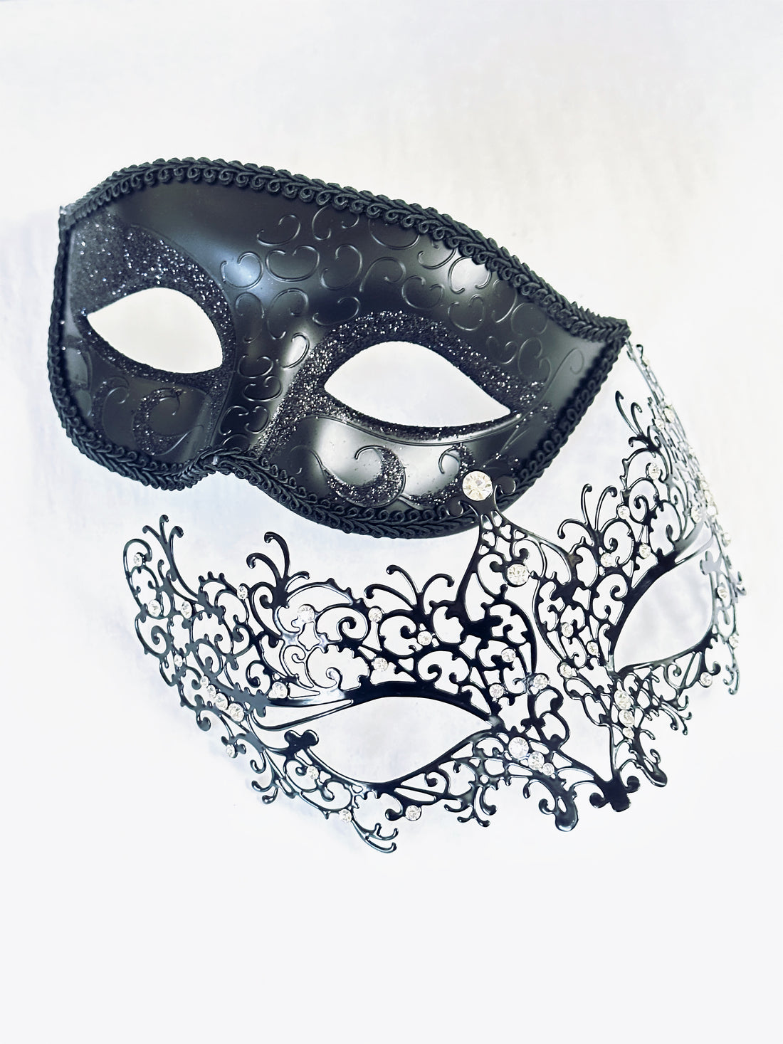 Black Venetian couples masquerade masks featuring a delicate filigree design for women and a glitter-accented scroll mask for men, perfect for elegant events and themed parties.

