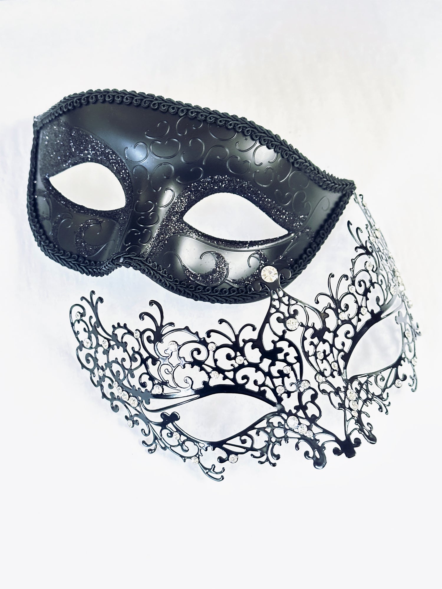Black Venetian couples masquerade masks featuring a delicate filigree design for women and a glitter-accented scroll mask for men, perfect for elegant events and themed parties.

