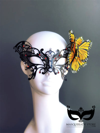 Black filigree masquerade mask with rhinestones and yellow butterfly accent, perfect for costumes and balls.