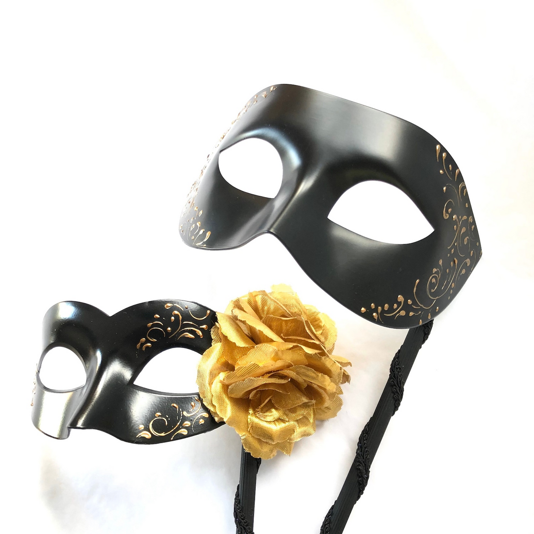 Black and gold masquerade couples mask set with one men’s Volto mask and one women’s Colombina mask with golden flower and handheld stick.