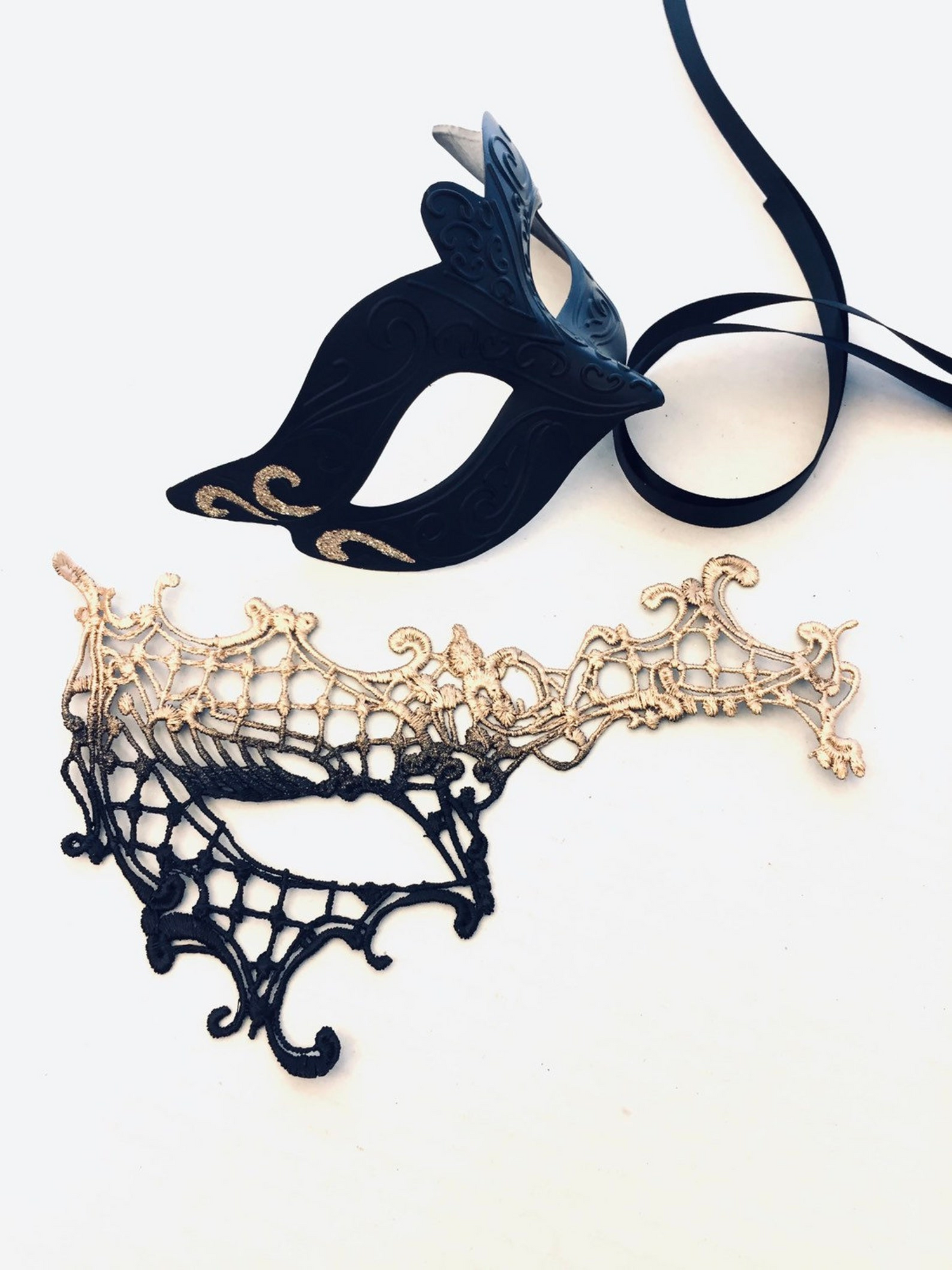 Black and gold masquerade couple’s mask set with a lace women’s mask and a sculpted men’s mask featuring scroll accents.