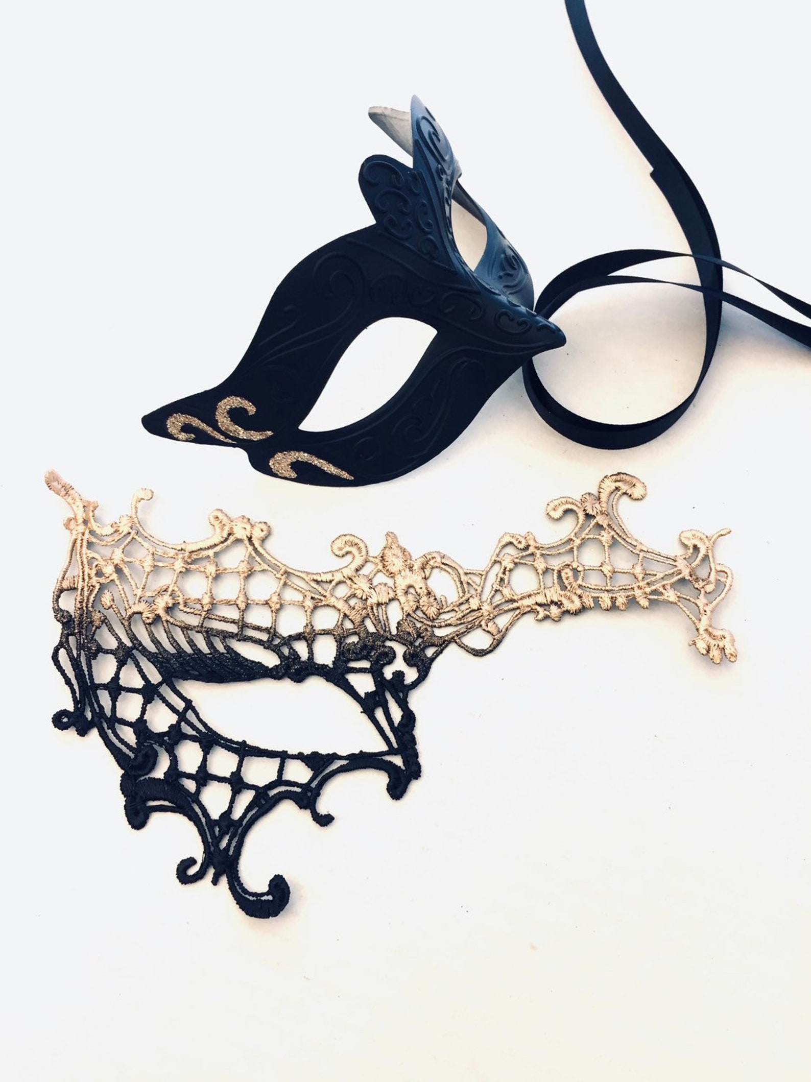 Black and gold masquerade couple’s mask set with a lace women’s mask and a sculpted men’s mask featuring scroll accents.