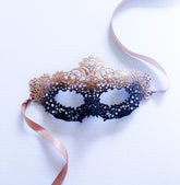 Elegant black and gold masquerade mask with filigree lace and ribbon ties