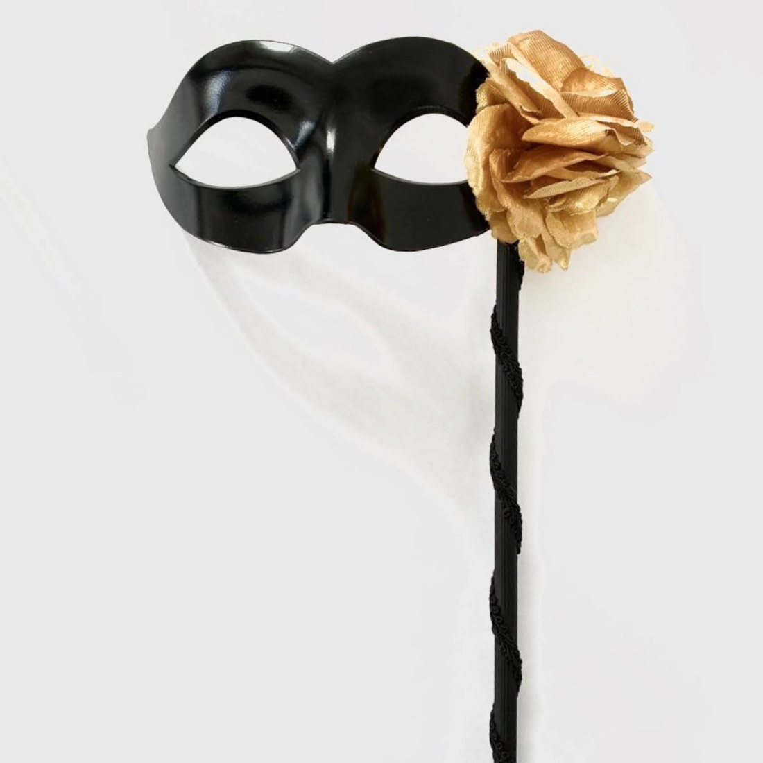 Black women’s masquerade mask with a golden flower accent on a handheld stick, designed in Colombina style for Venetian masquerade balls and parties.