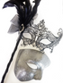Couple’s masquerade mask set with a black lace handheld feather mask for women and a silver scrollwork mask for men.