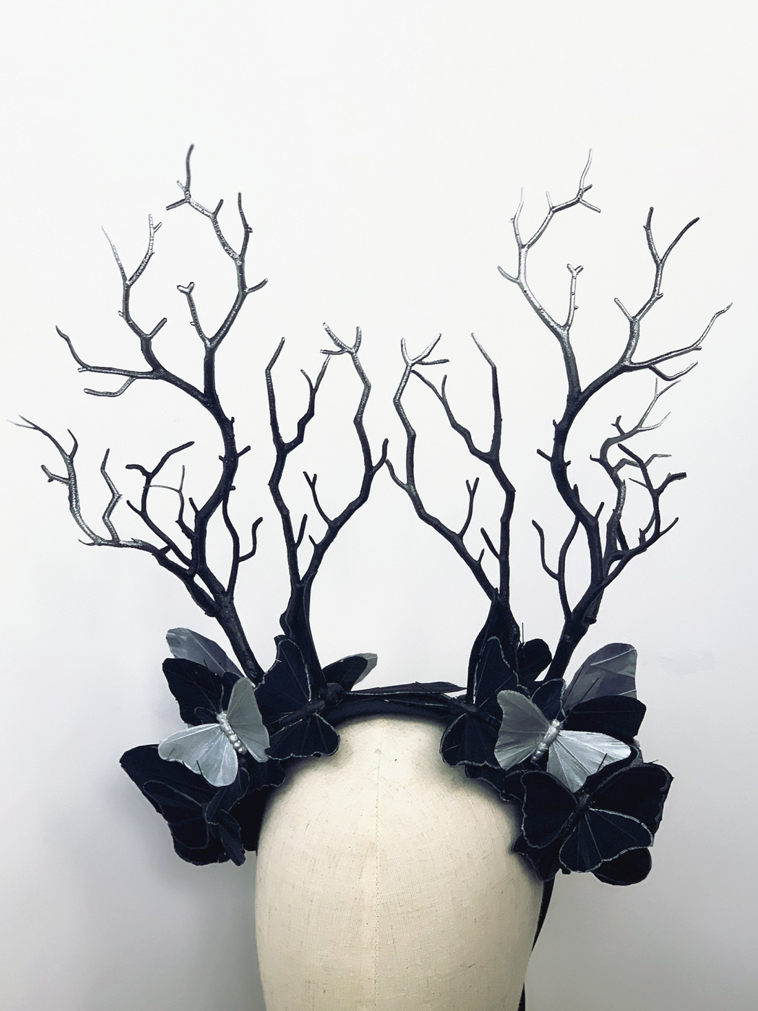 Elegant black masquerade crown with branch antlers and silver butterflies, perfect for gothic or woodland looks.