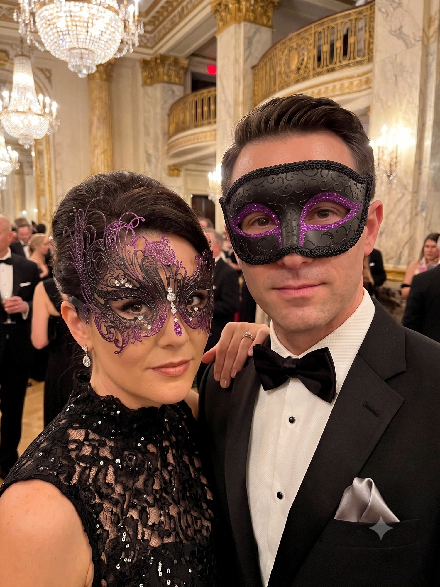 Black and purple Venetian couples masquerade mask set featuring a men’s black eye mask with amethyst glitter accents and a women’s swan filigree rhinestone mask for masquerade balls, Mardi Gras, black tie parties, and formal costume events.