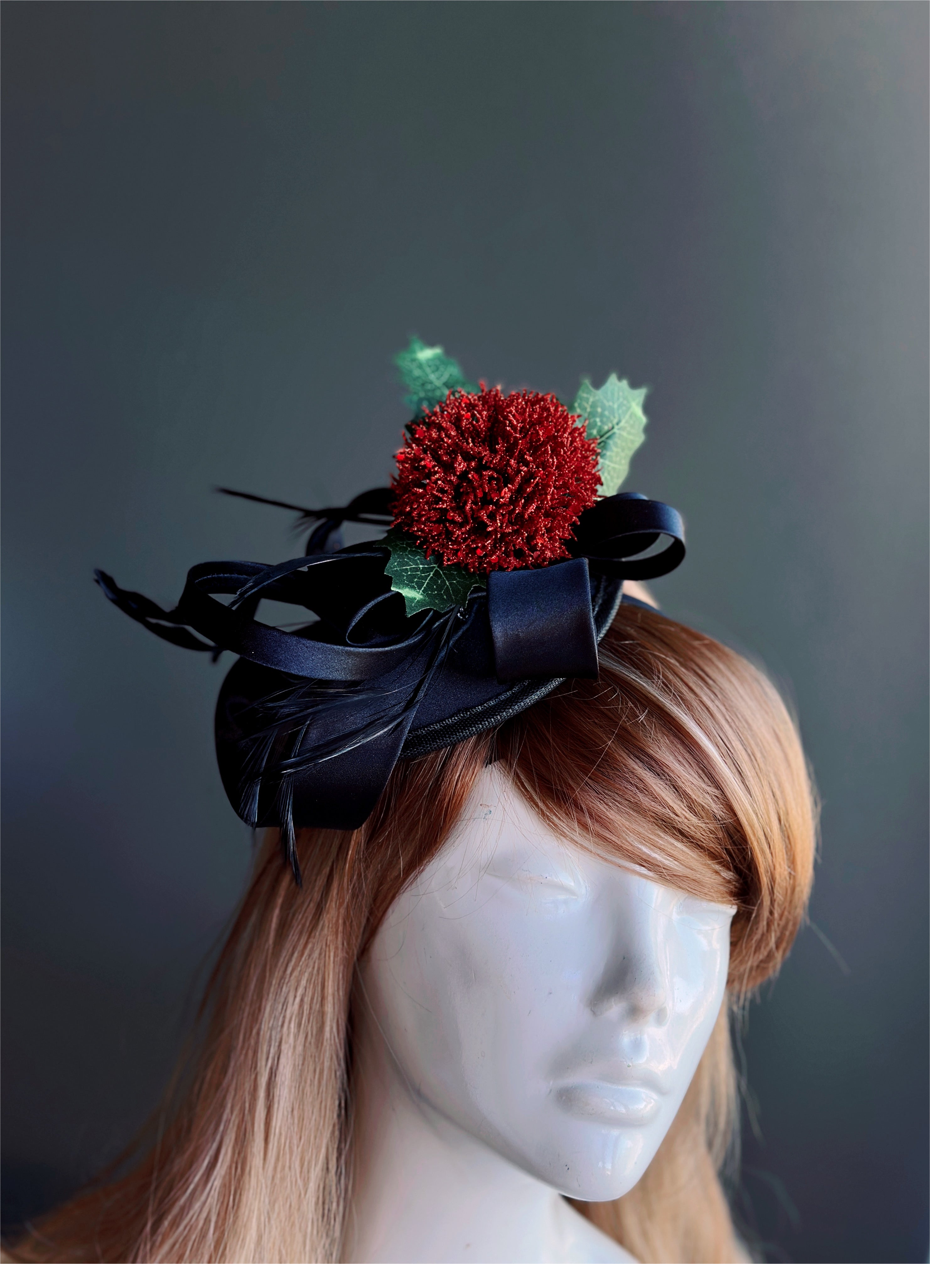 Black fascinator hat with red pom flower and green holly leaves, holiday headpiece for women, perfect for Christmas, Derby, and masquerade.