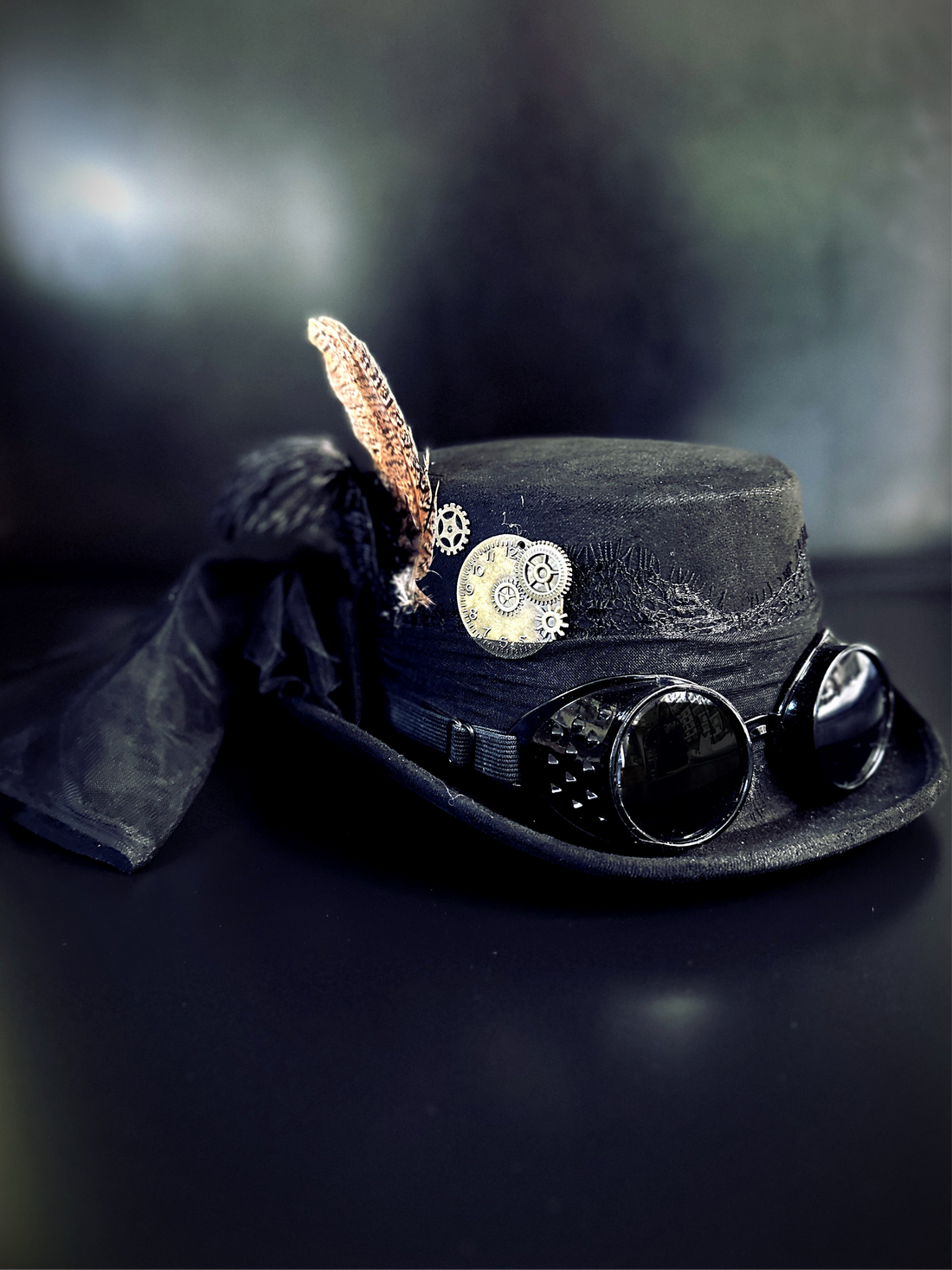 Gothic steampunk costume hat with black fabric, goggles, and vintage embellishments