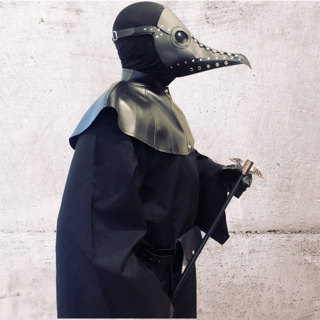 Man in gothic black leather plague doctor mask and robe with walking stick
