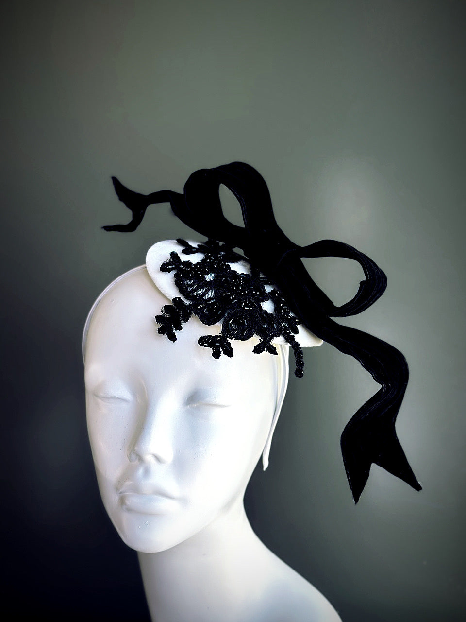 Elegant black and white fascinator hat with oversized bow and lace applique, designed for weddings, derby fashion, and tea parties.