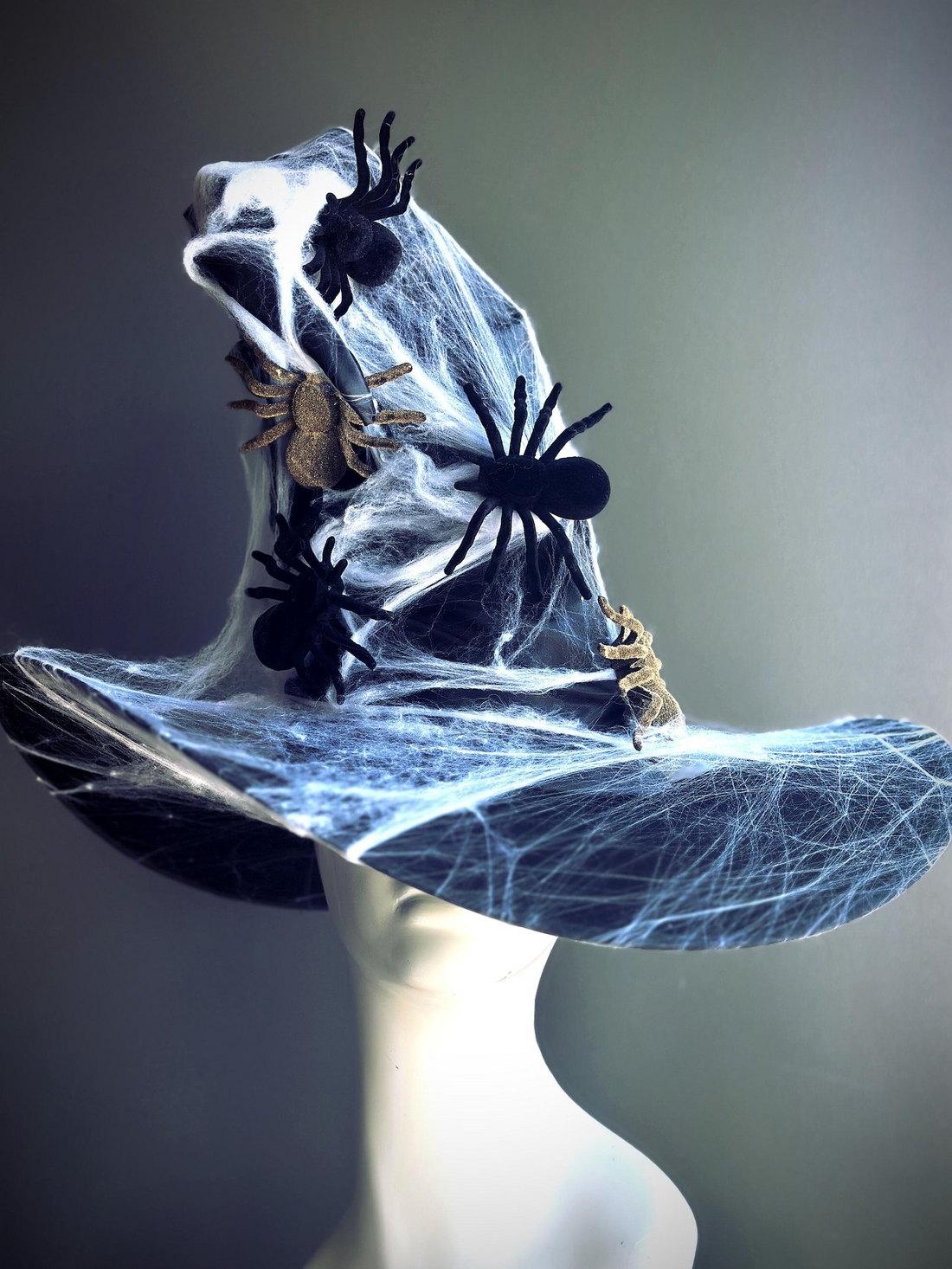 Black witch hat with spider web overlay and black and gold spider accents for Halloween.