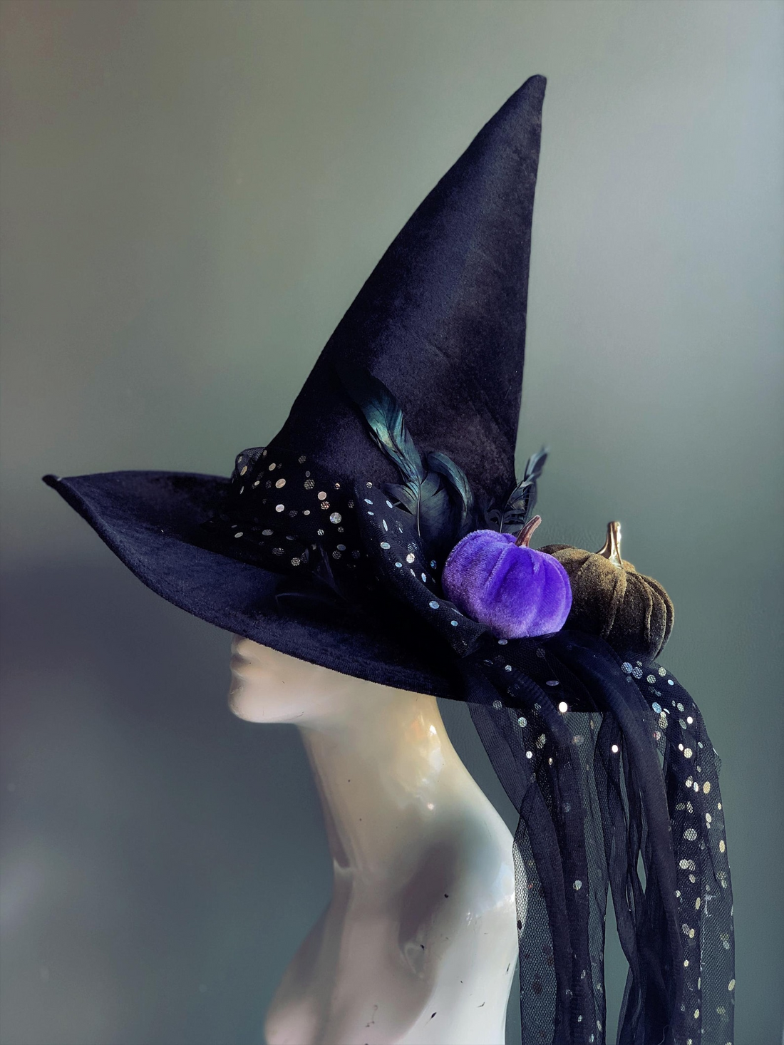 Black velvet witch hat with velvet pumpkins, feathers, and sequin veil for Halloween costumes.