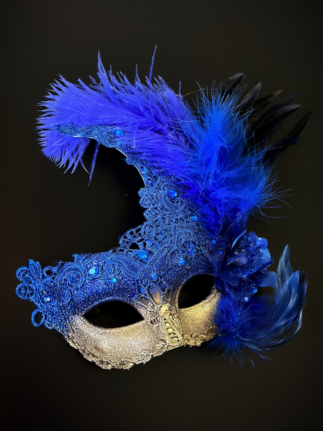 Elegant feather masquerade mask in cobalt blue with gold lace and flower accents