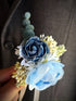 Blue floral boutonniere with mixed petals and eucalyptus accent, perfect for formal events