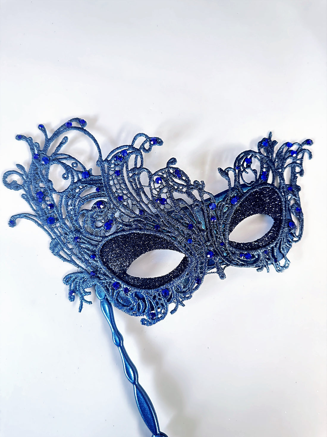Blue lace masquerade mask with rhinestones and stick handle for masquerade ball or prom.