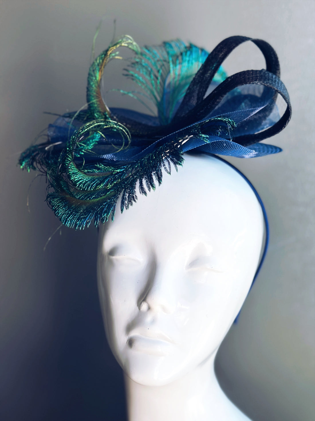 Navy blue feathered fascinator featuring peacock plumes and sculptural loops for formal fashion or parties