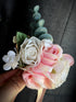 Romantic groom boutonniere with soft blush roses and greenery, perfect for formal occasions