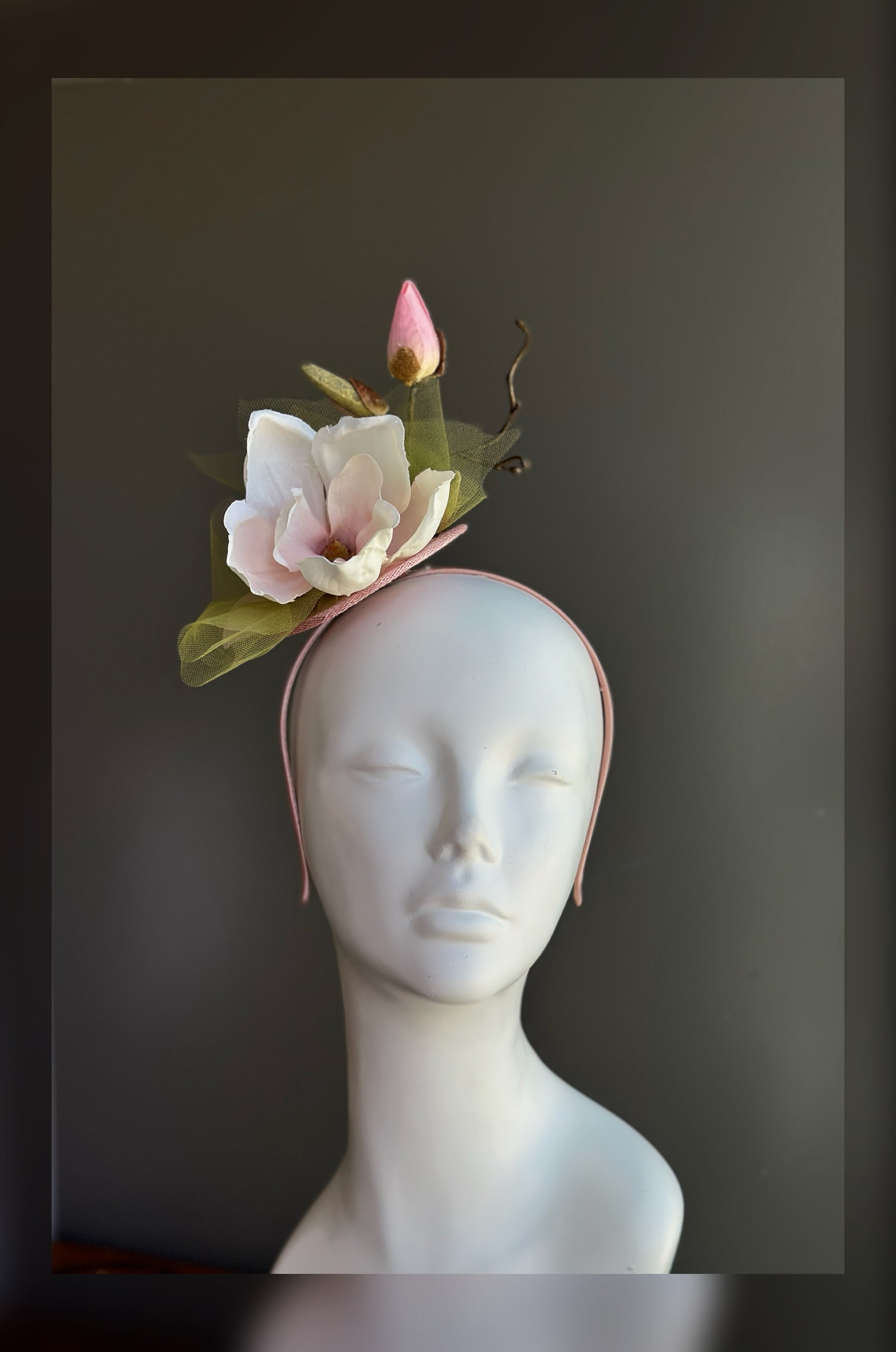 Blush pink magnolia fascinator hat with soft petals for weddings and garden party occasions.