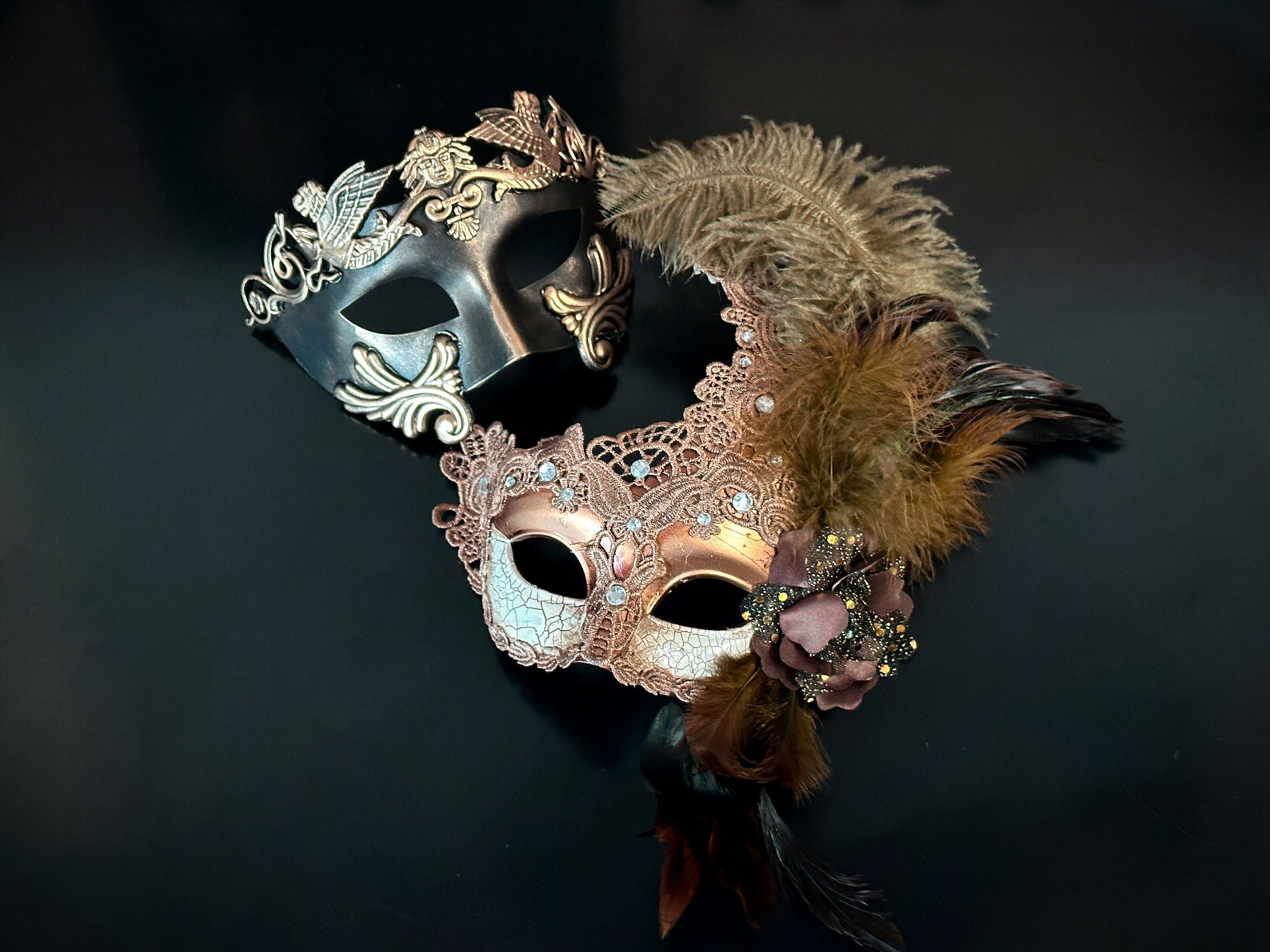 Elegant bronze and rose gold couples masquerade mask set with feathers, lace, rhinestones, and baroque details.