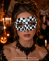 Checkmate Whisper black and white masquerade mask with irregular checker pattern, sculpted eye openings, and monochrome theatrical styling.