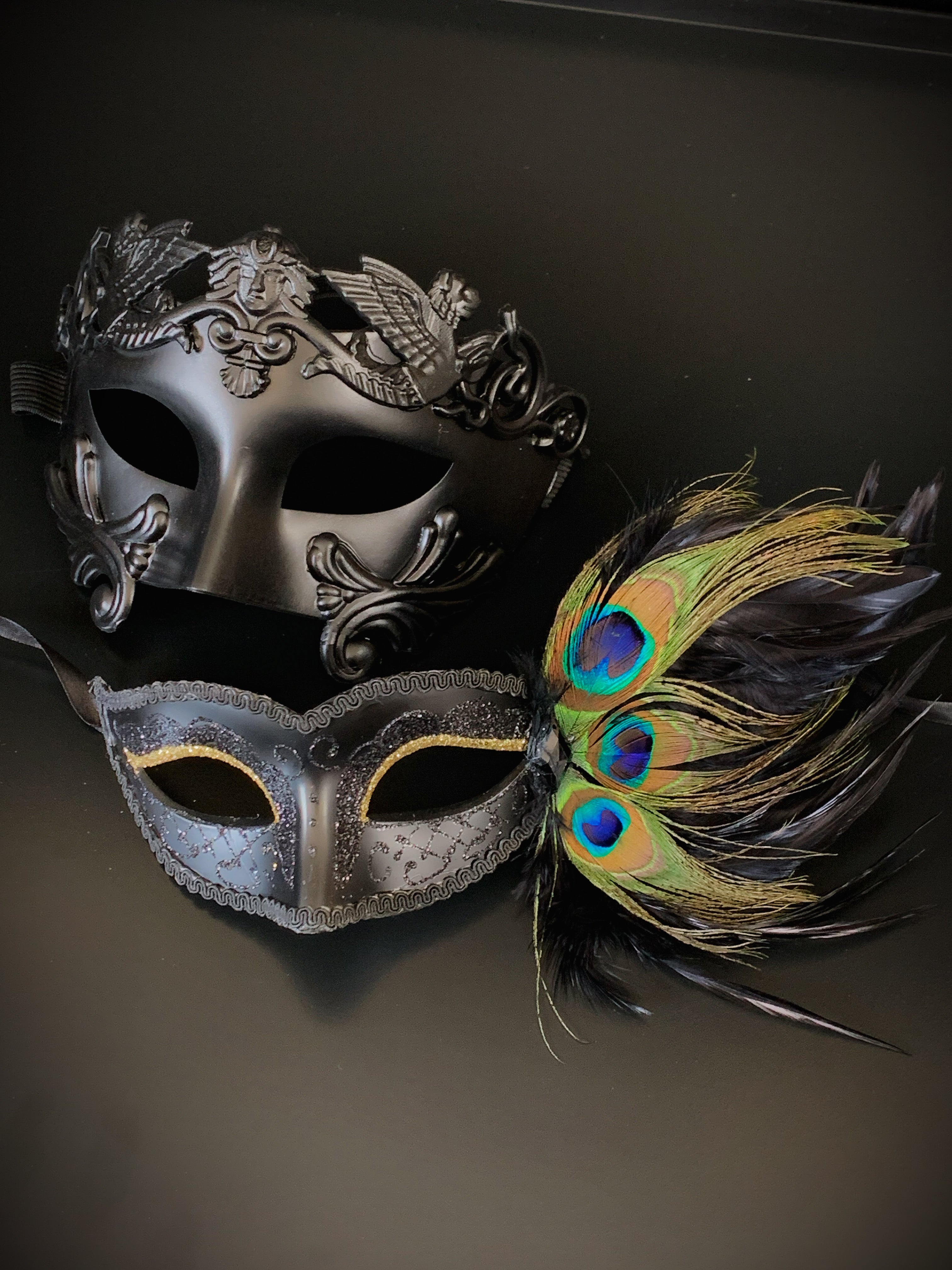 Couples mask set with a black gladiator mask for the man and a black peacock mask with gold glitter eyes.