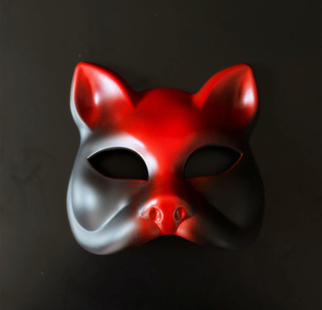 Red and black cat masquerade mask with sculpted feline shape for theatrical and costume events.