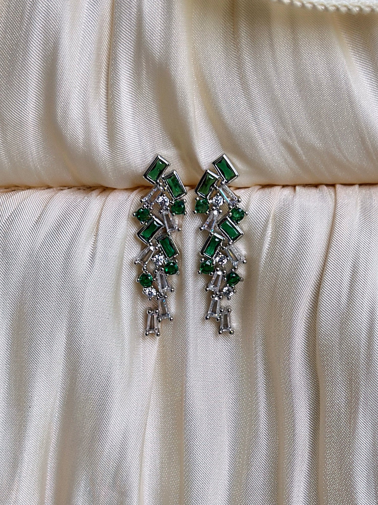 Emerald green geometric drop earrings with silver setting and cascading crystal accents.