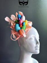 Pale pink Easter fascinator full of glittered eggs, feathers and fabric bows attached on a matching headband