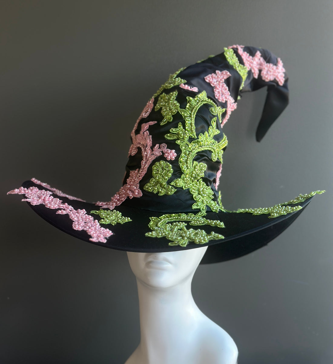 Black witch hat with pink and green beaded floral embroidery and wide brim design.