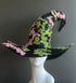 Black witch hat with pink and green beaded floral embroidery and wide brim design.