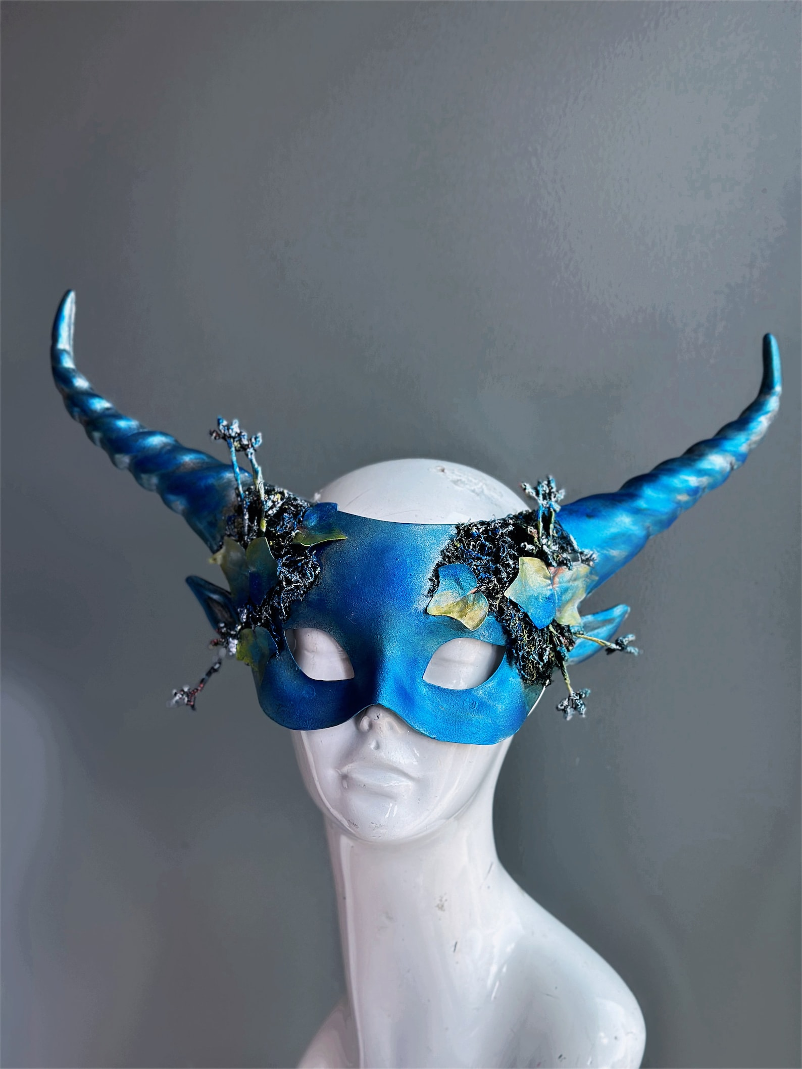 Blue masquerade mask with twisted horns and ivy leaf woodland accents.