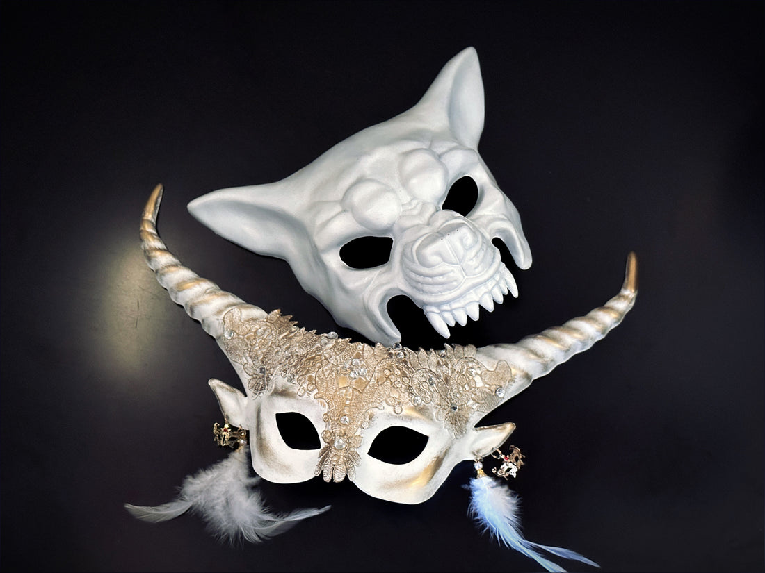 Silver-gray fantasy elf horn masquerade mask with floral filigree, gear charms, and black feather details