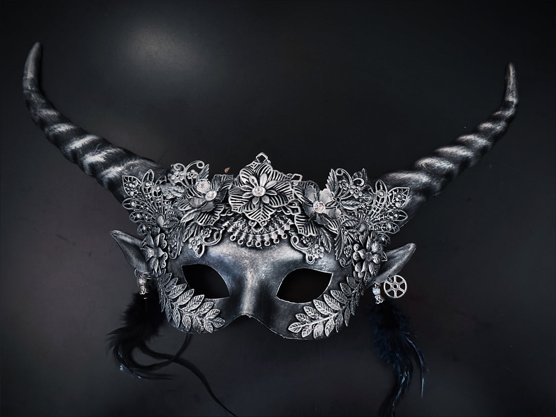 Silver fantasy horn masquerade mask with floral filigree, black feathers, elf ears, and steampunk gears