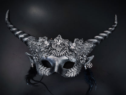 Silver fantasy horn masquerade mask with floral filigree, black feathers, elf ears, and steampunk gears