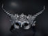 Silver fantasy horn masquerade mask with floral filigree, black feathers, elf ears, and steampunk gears