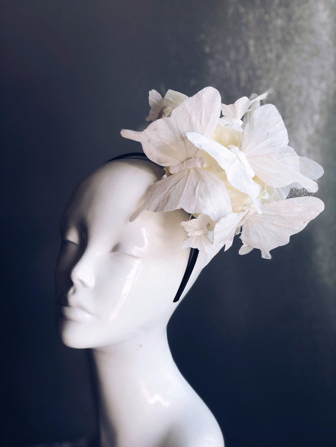 Fascinator hat with white butterflies on a white flower.