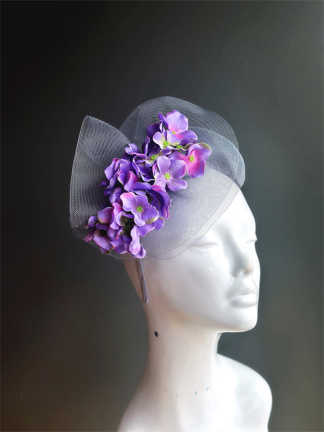 Purple flowers on a silver fascinator tulle base with a headband.