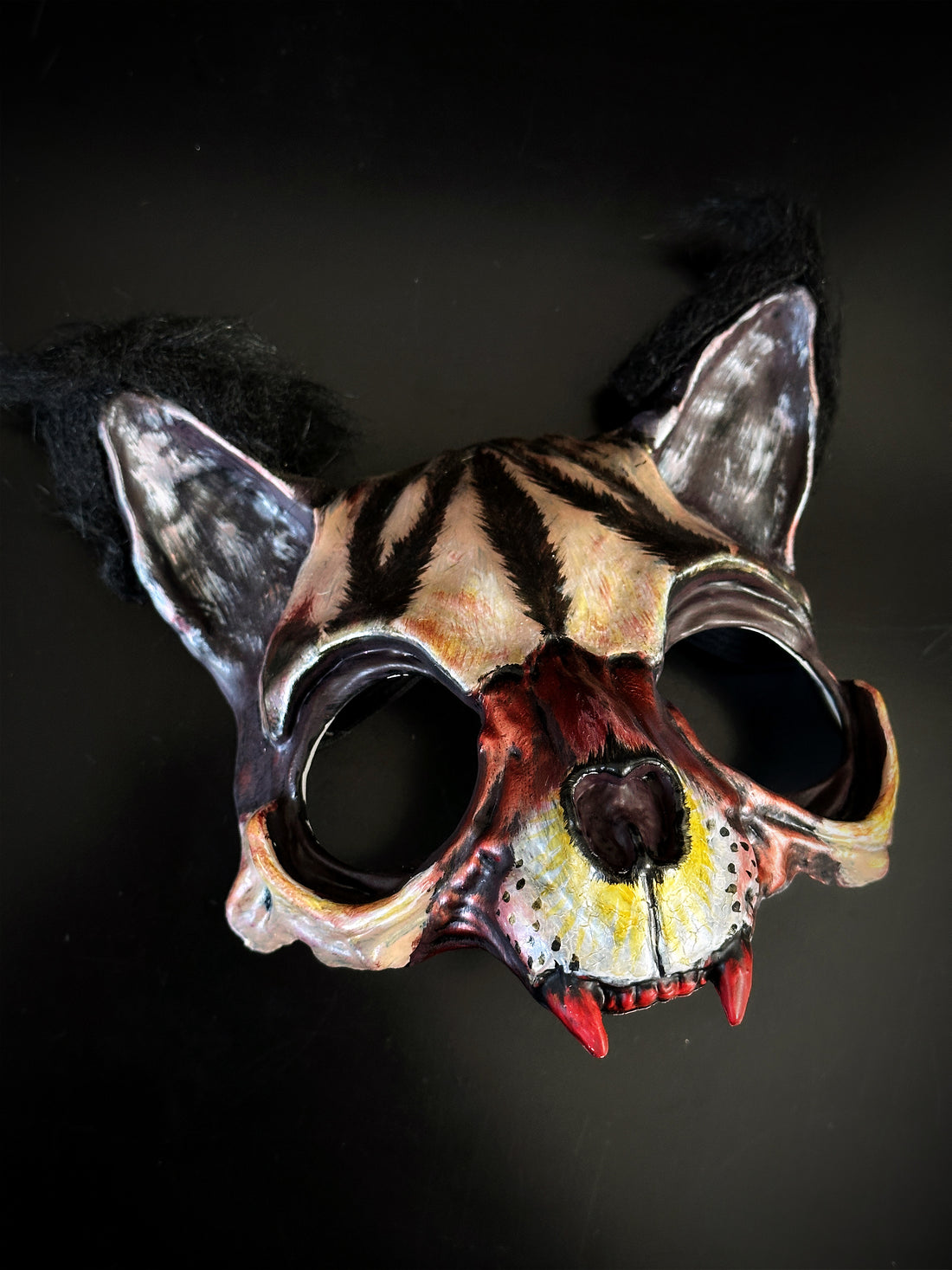 Feral beast masquerade mask with hand-painted skull details, faux fur ears, and red fangs for horror costumes and Halloween cosplay.