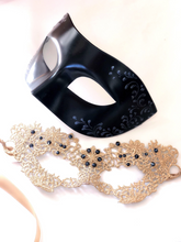 Couples masquerade mask set featuring black vegan leather men’s mask and gold lace women’s mask with gemstone accents.