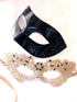 Couples masquerade mask set featuring black vegan leather men’s mask and gold lace women’s mask with gemstone accents.