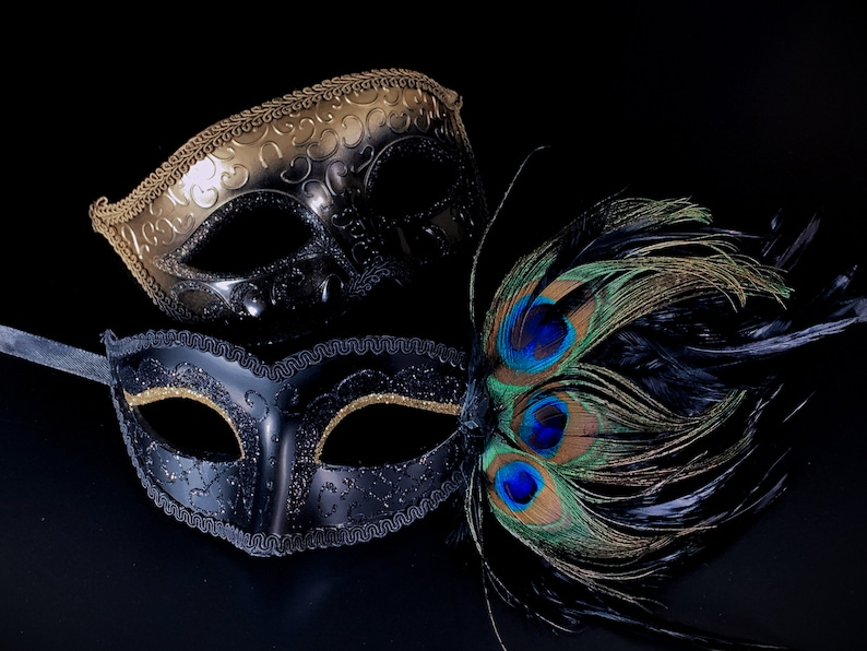 Gold embossed men’s masquerade mask and black women’s peacock feather masquerade mask with glitter accents.