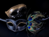 Gold embossed men’s masquerade mask and black women’s peacock feather masquerade mask with glitter accents.