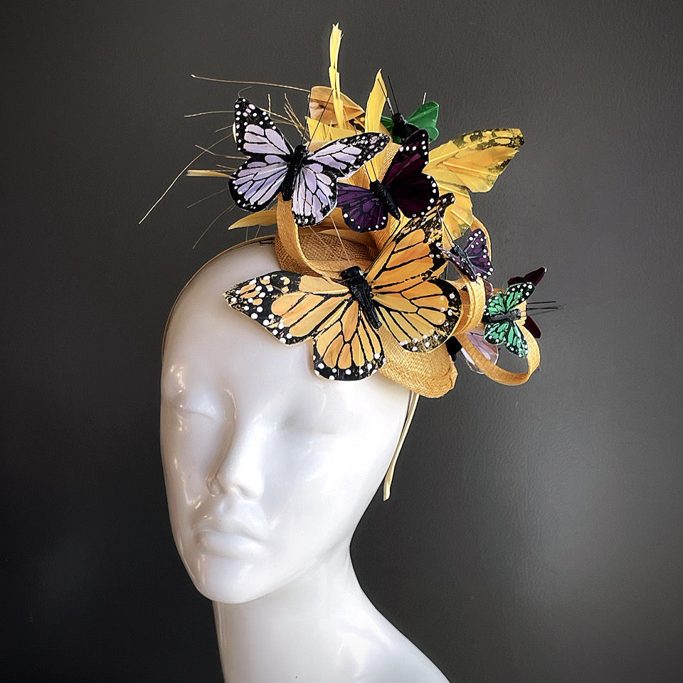 Gold Flutter Majesty Fascinator with butterflies in shades of gold, purple, and green, set atop an elegant gold base. 
