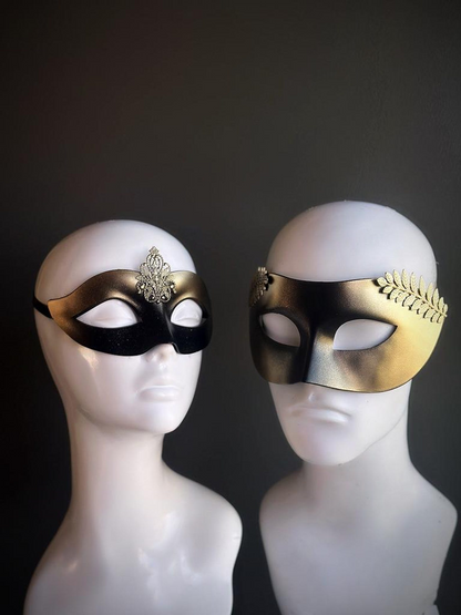 Black and gold couples masquerade masks with laurel design for men and filigree crest for women.