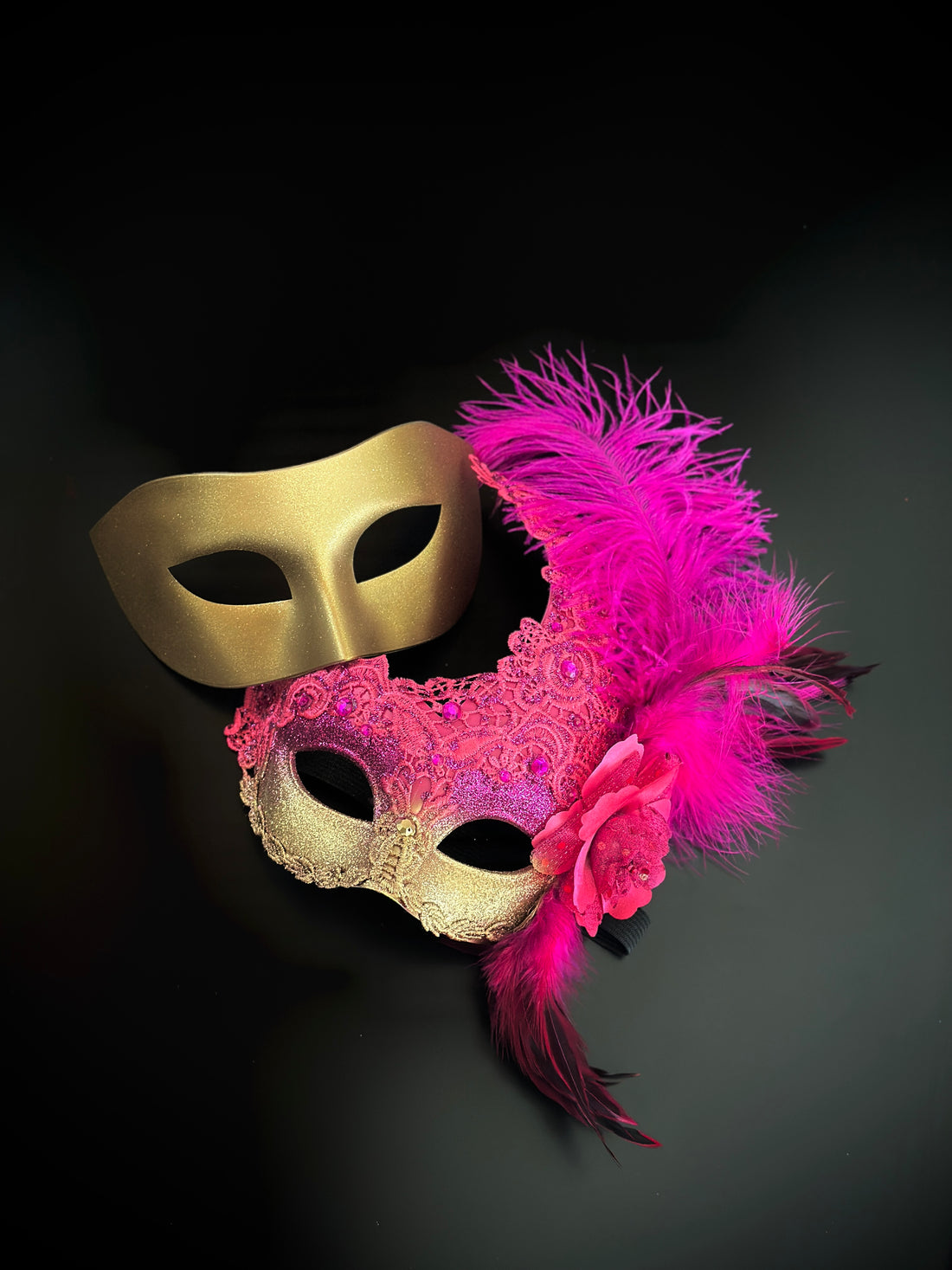 Matching masquerade masks in gold and pink with floral and feather embellishments