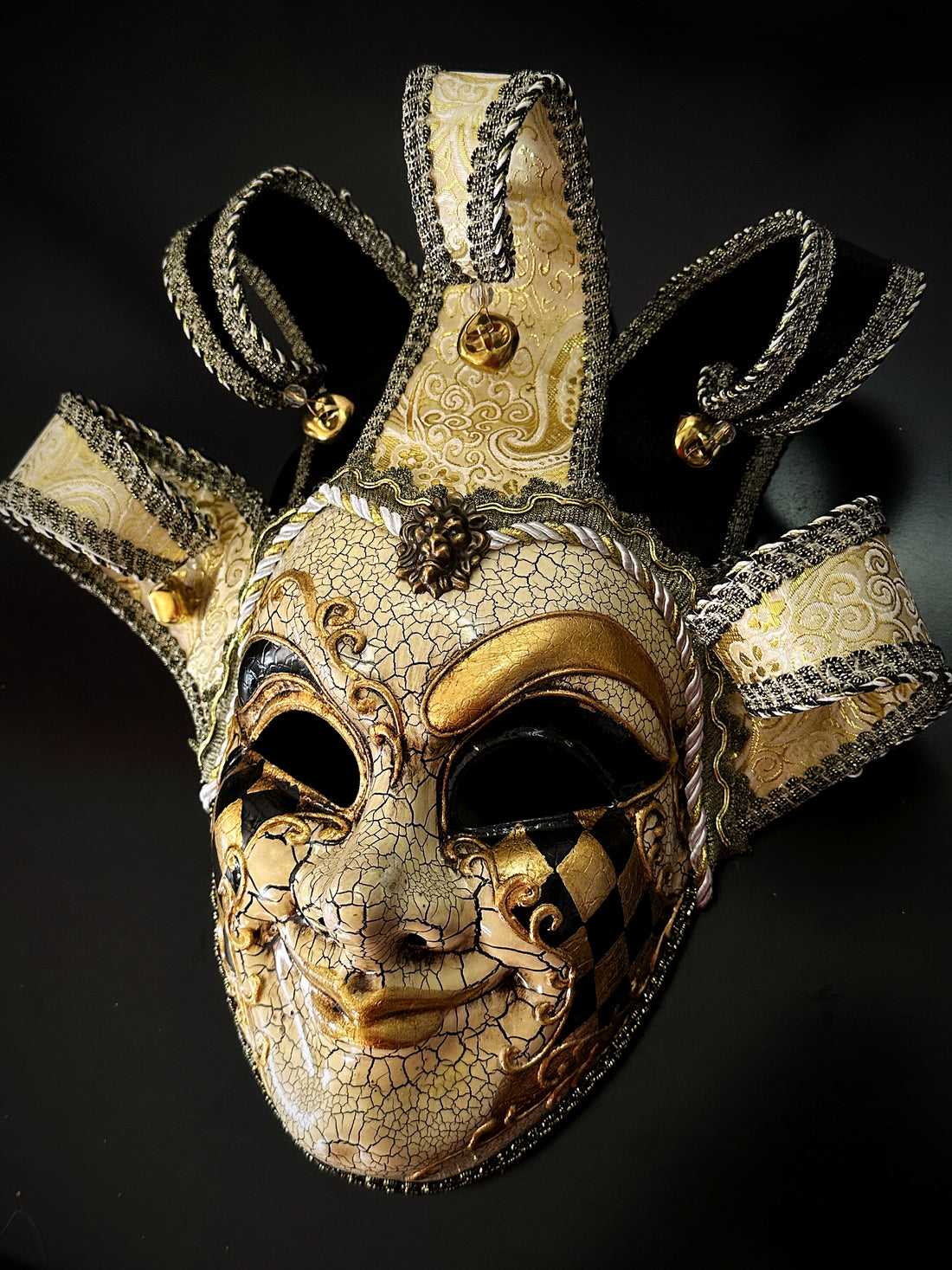 Gold and black Venetian jester mask with ornate baroque detailing and harlequin diamonds.