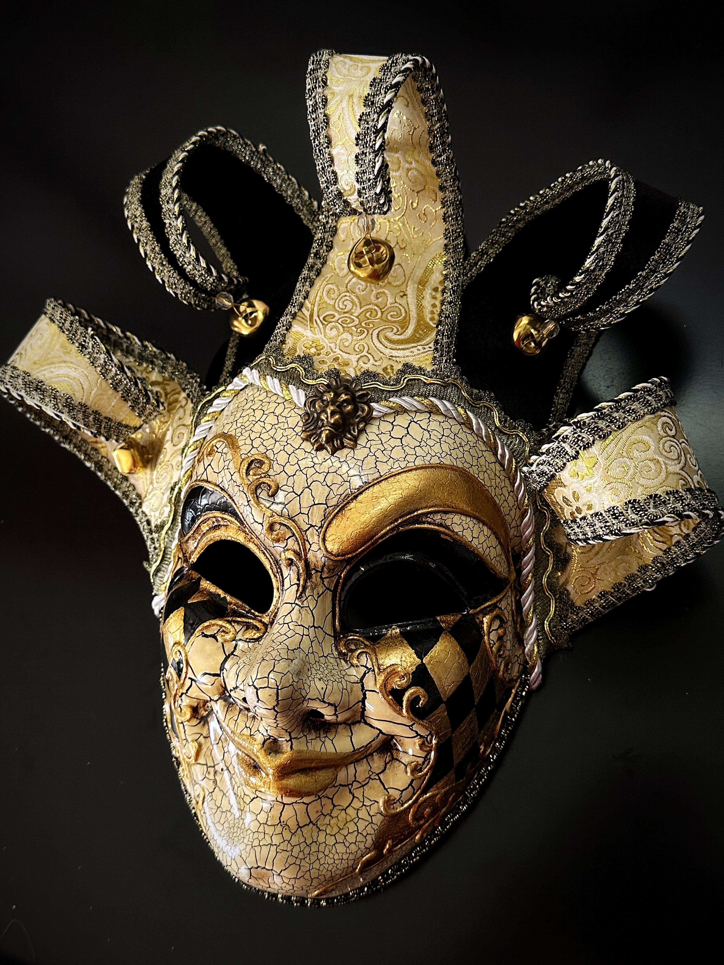 Gold and black Venetian jester mask with ornate baroque detailing and harlequin diamonds.