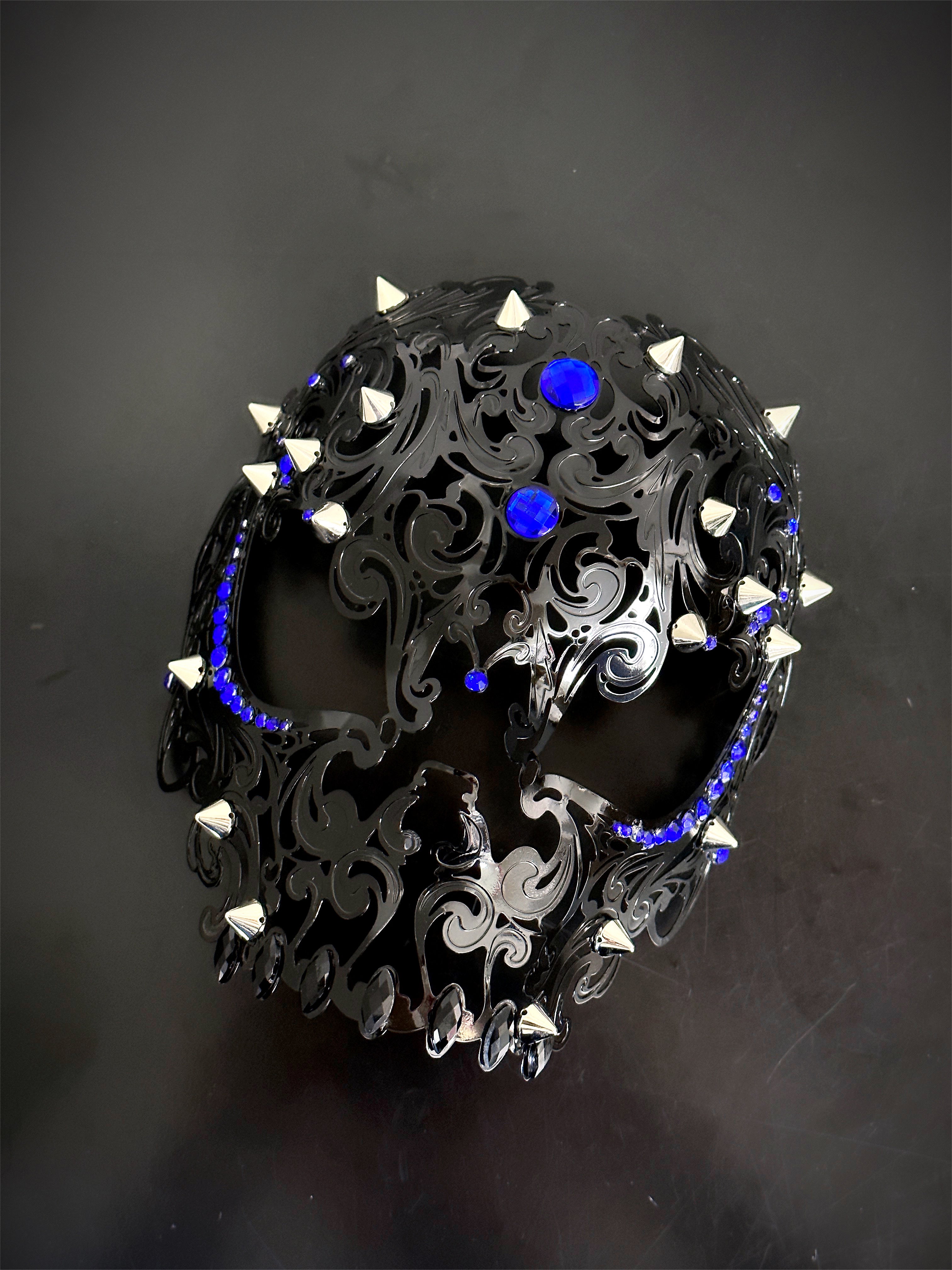 Black skull masquerade mask with silver spikes and royal blue rhinestones