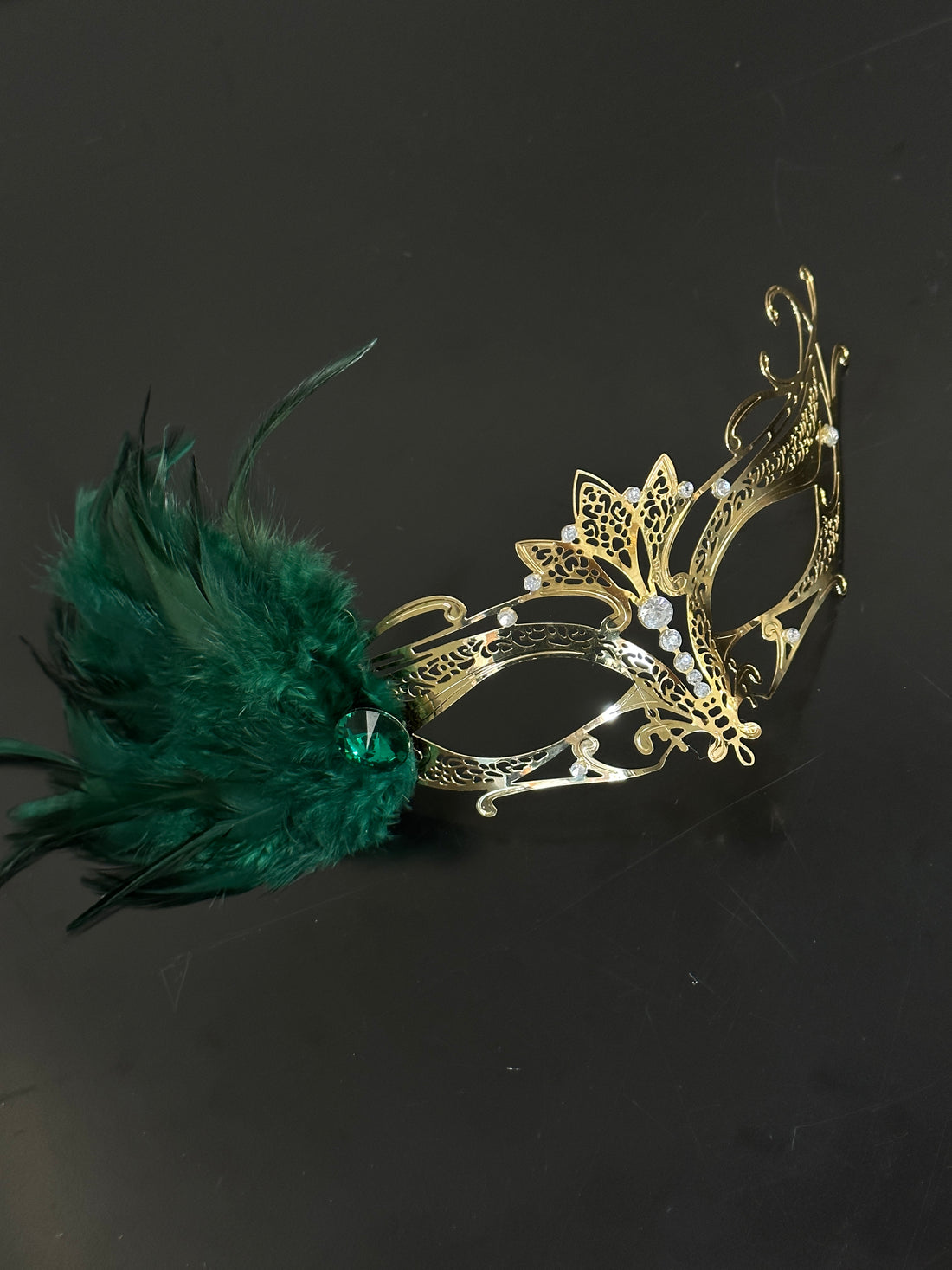 Elegant gold feather mask featuring emerald green plumage accent